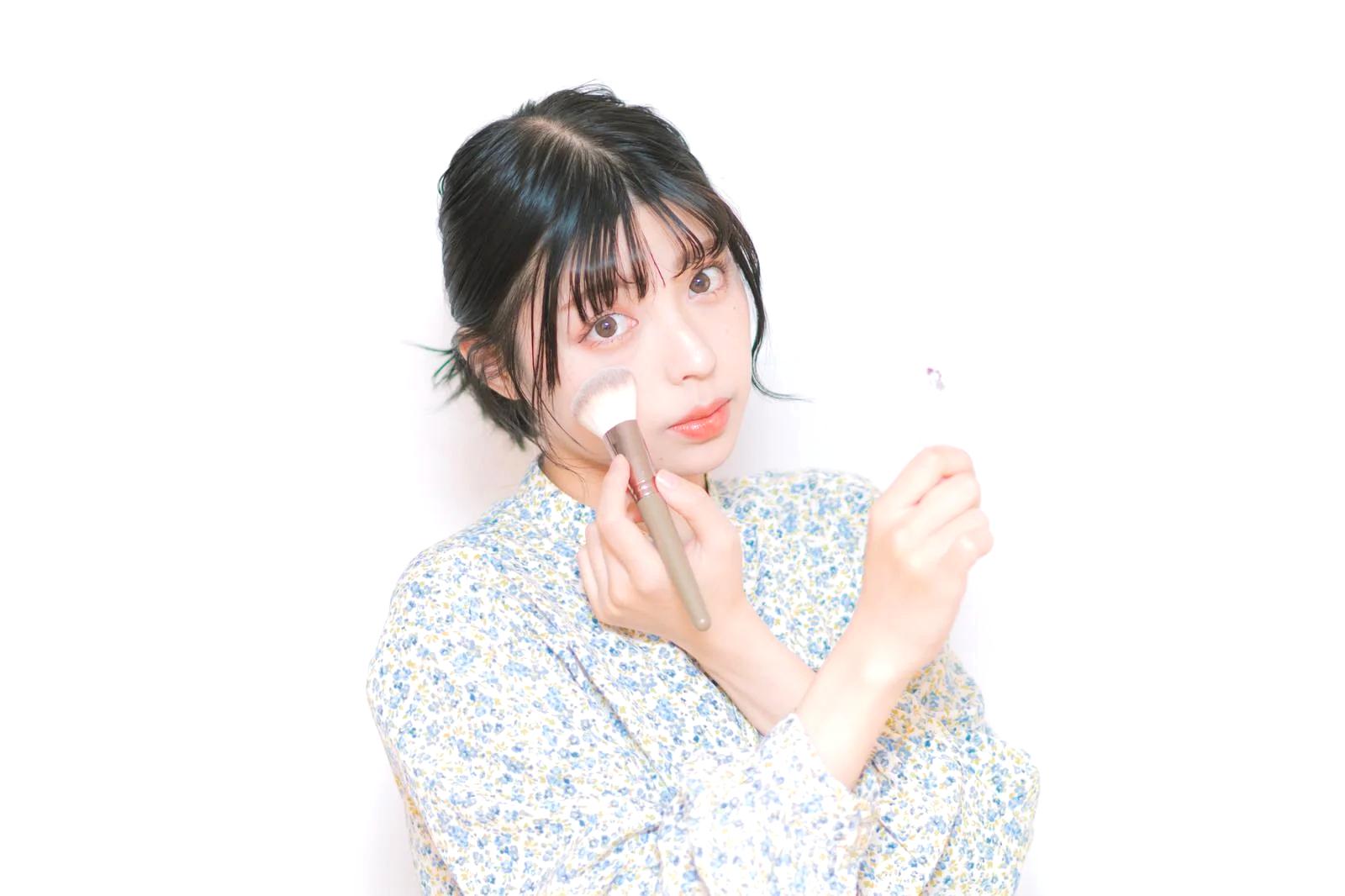 メイクの上から日焼け止めを塗り直す外出中の女性の手元