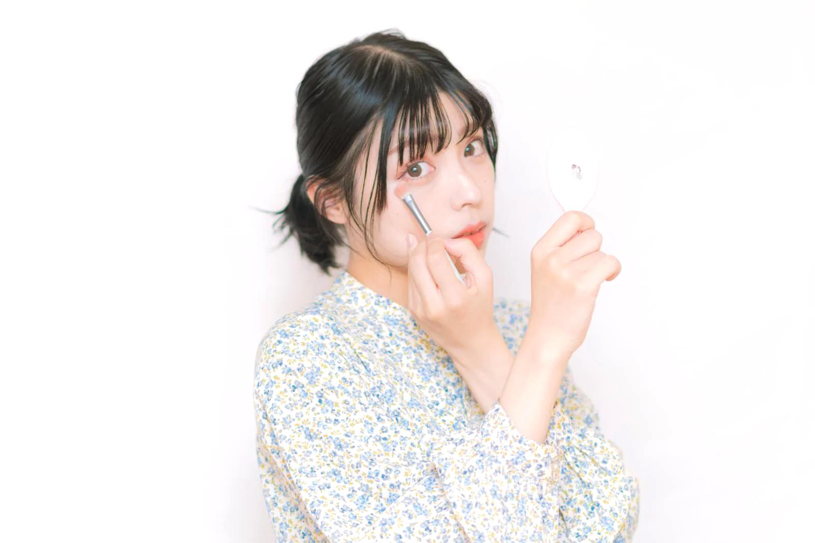 スマホ画面の光を浴びながら肌悩みを気にする女性