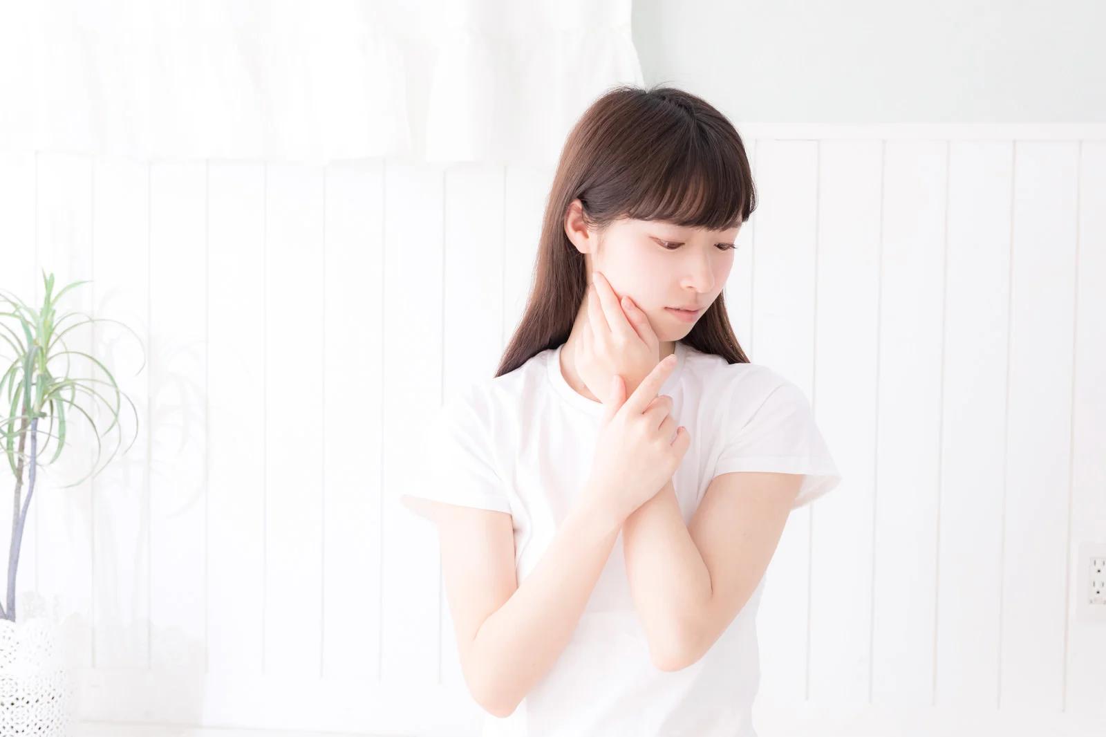 外出中に鏡を見ながら日焼け止めを塗り直している女性