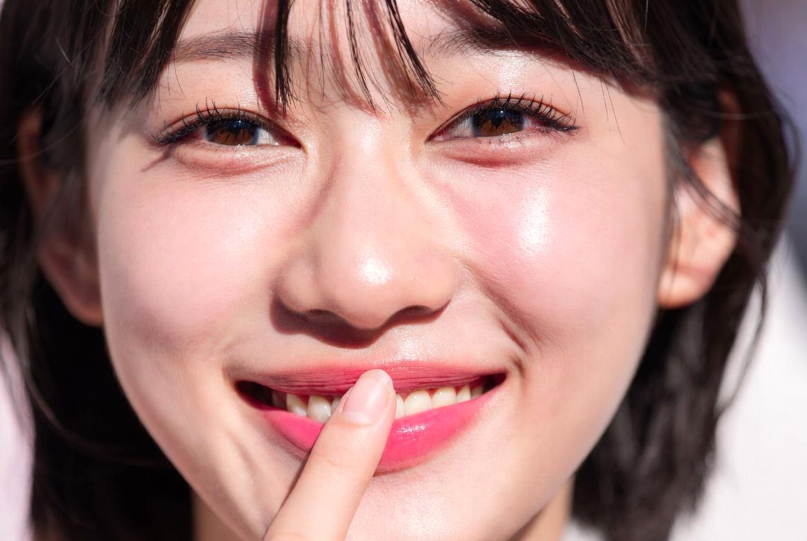 鏡の前で笑顔を見せる女性。ほうれい線が目立たず、健康的で若々しい口元のイメージ
