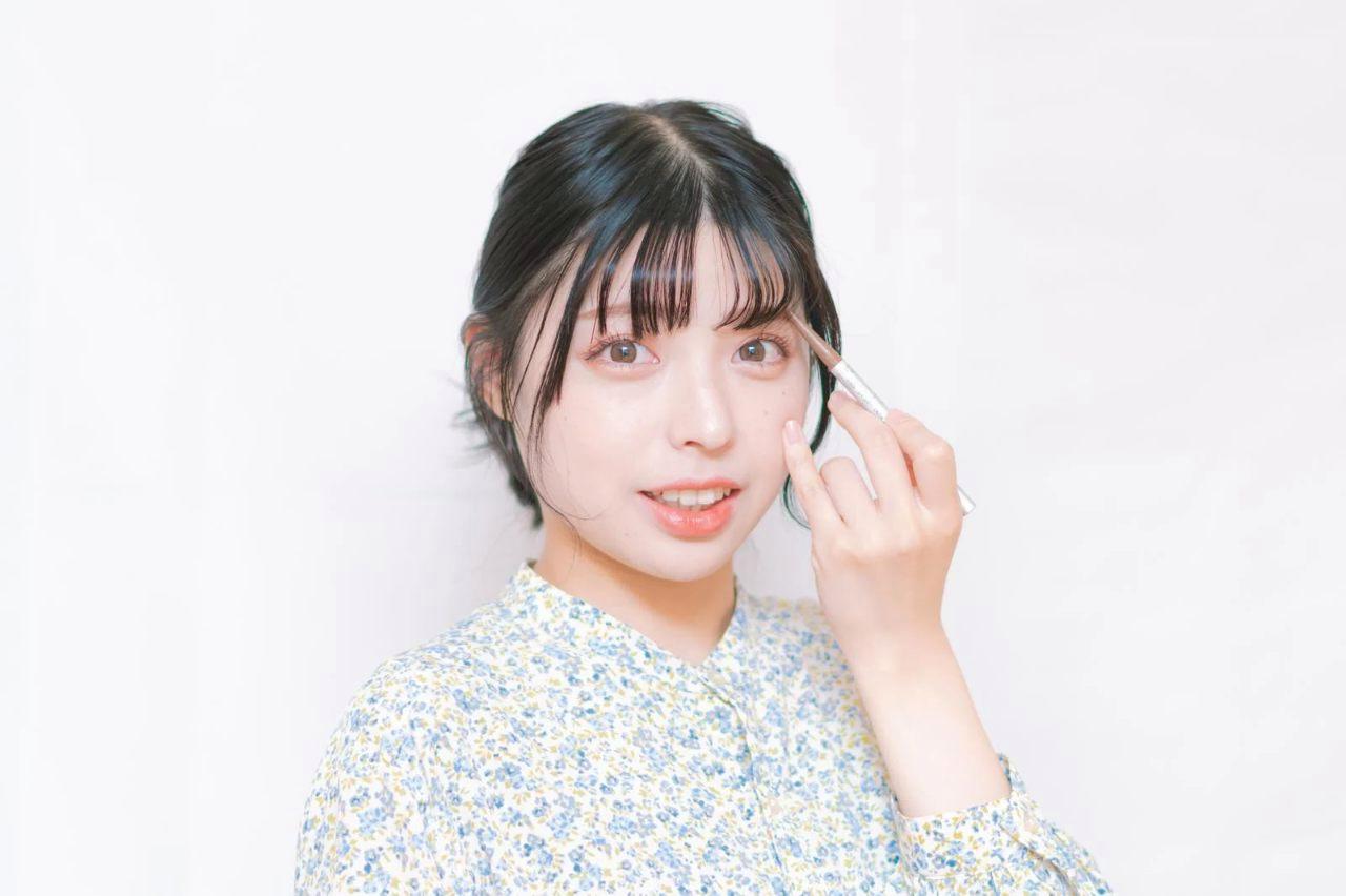 鏡を見ながらハサミとコームで眉毛を整える大人の女性