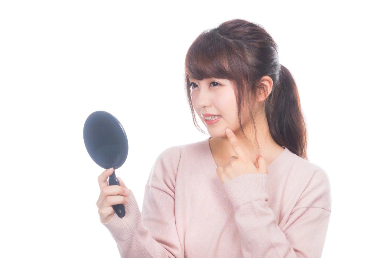 スマホを見ながらうつむき姿勢でいる女性。首のシワとほうれい線が強調されるイラスト