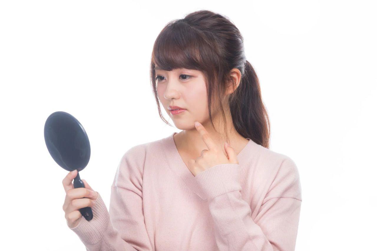 乾燥しわが気になる女性が鏡の前で肌の状態を確認している