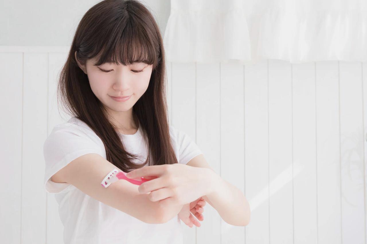 鏡の前でほうれい線を気にする女性の顔。肌の乾燥やたるみが気になる口元を指でそっと触れている様子