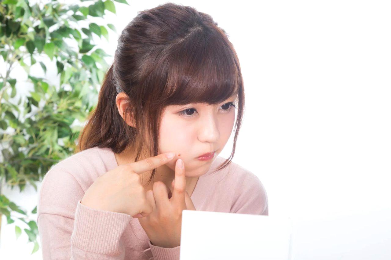 ラーメンを前にしながら肌状態を気にする大人の女性のイメージ
