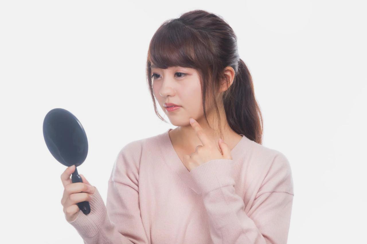 夜のソファでお菓子を食べる大人の女性。間食と肌トラブルの背景を表現