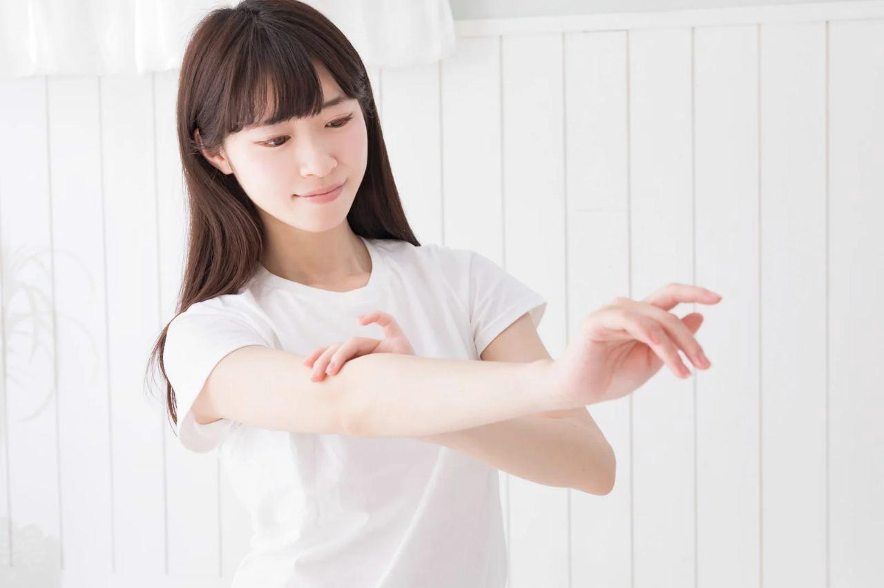 入浴後に保湿ケアをする女性とスキンケア用品