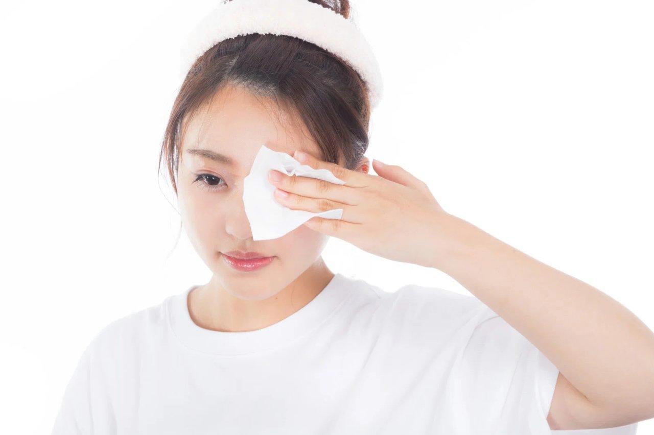 メイク道具の前に座りながら泥パックをしている女性の背中