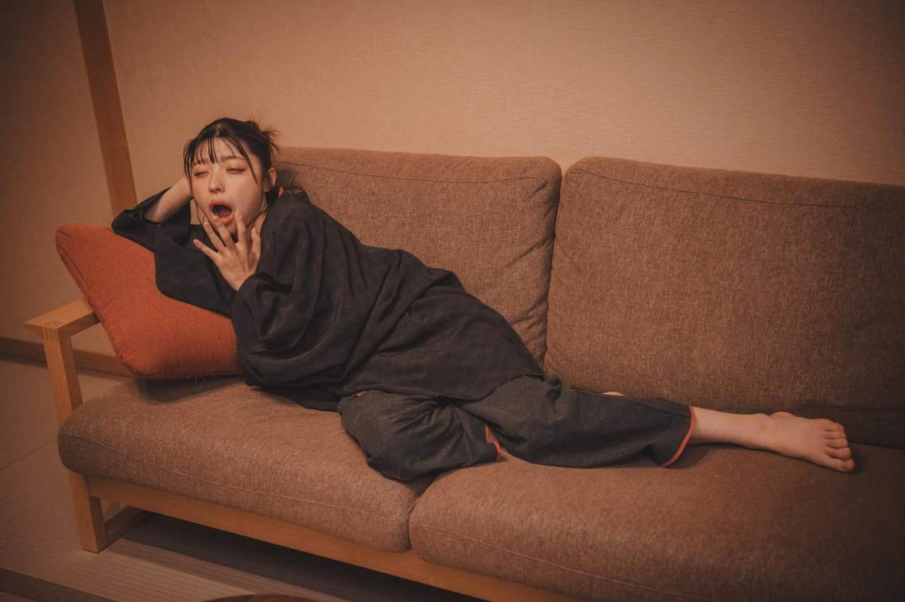 朝起きて鏡の前に立ち、眠気とむくみを感じている女性のイメージ画像