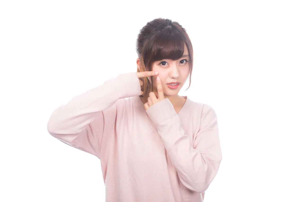 思春期の女性が頬のニキビを気にして鏡を見ている様子