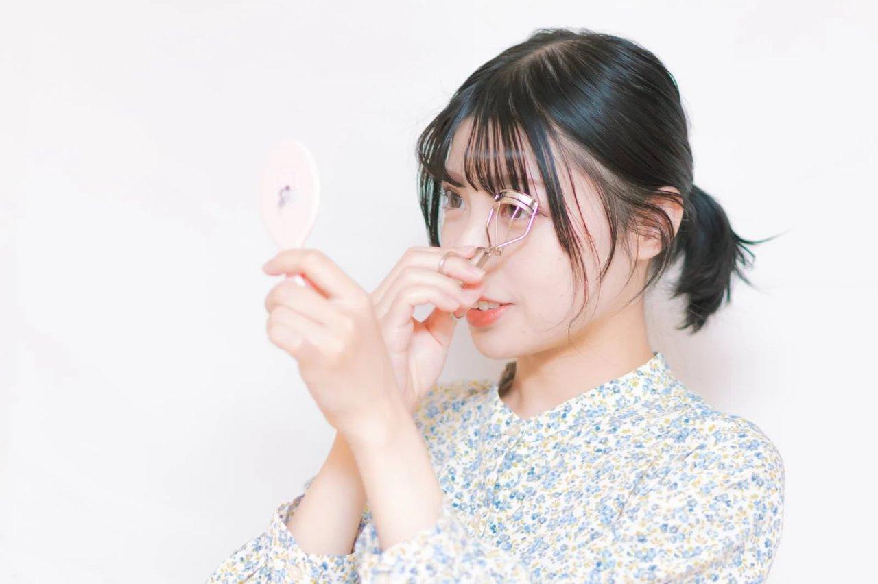深夜に暗い部屋でスマホを見つめ目元を疲れさせる若い女性の写真