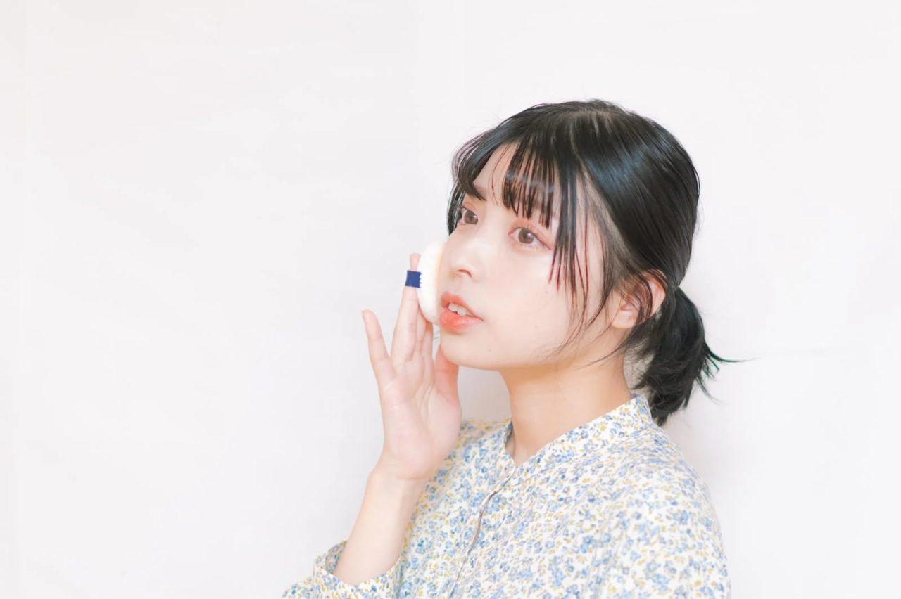 ティッシュと鏡でメイク直し前の肌を整える女性