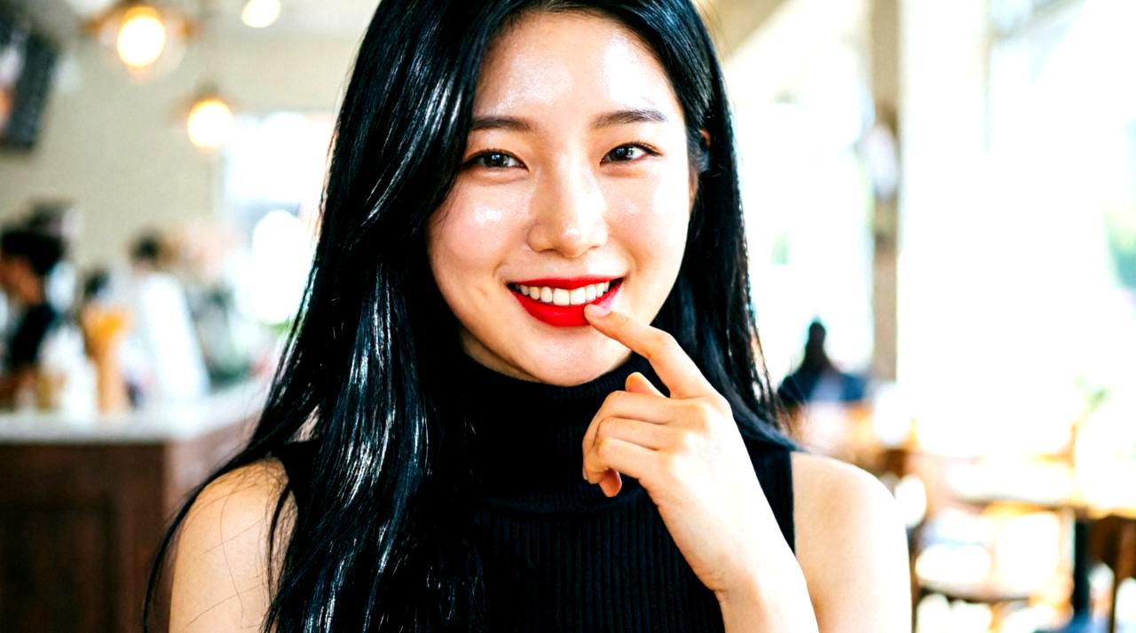 20代後半の女性が明るい笑顔で鏡に向かいスキンケアを楽しんでいる姿